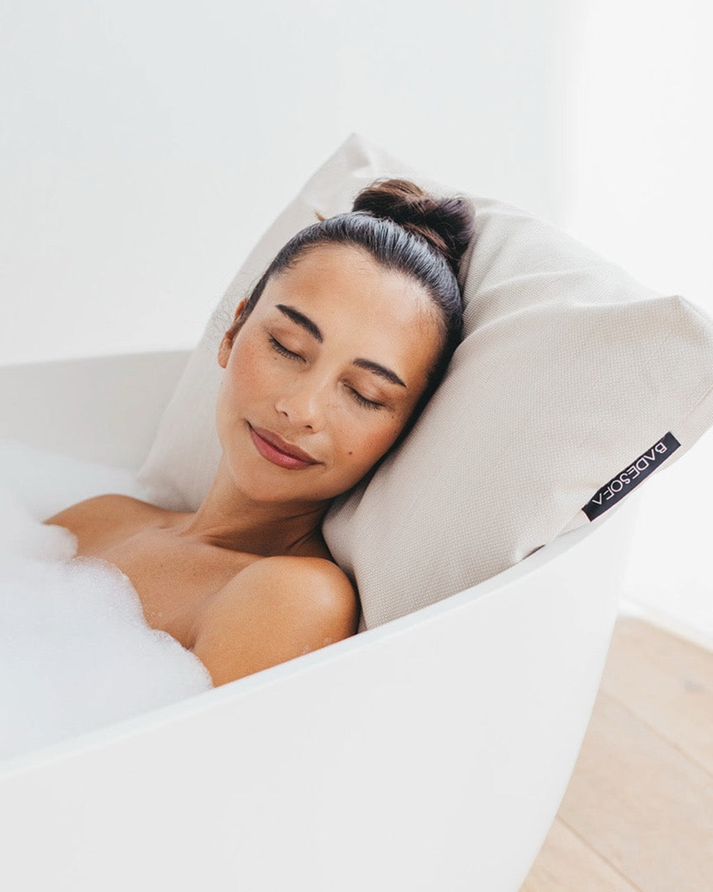 Perlmutt Badesofa Rückenkissen (Size Large) in einer freistehenden Badewanne, mit einer Frau, die sich entspannt anlehnt. $ Freistehende Badewanne | Size Large