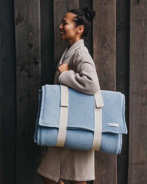 Frau trägt ein blaues Saunasofa über der Schulter.