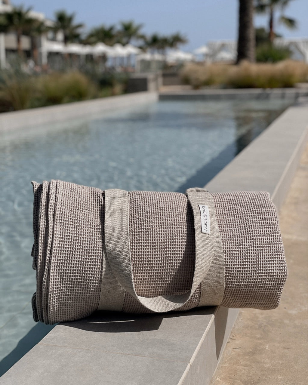 Ein zusammengerolltes Strandsofa liegt am Rand eines Pools.